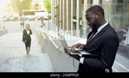 Homme d'affaires noir réussi travaillant sur un ordinateur portable en extérieur, se préparant à la réunion Banque D'Images