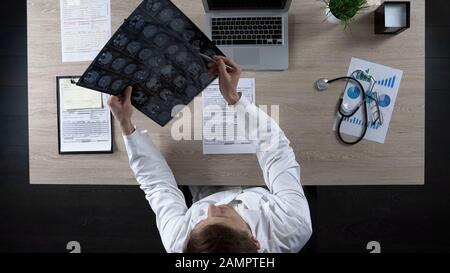 Neurochirurgien regardant l'IRM du cerveau humain pour diagnostiquer la maladie du patient, vue de dessus Banque D'Images