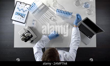 Les étudiants prennent des réactifs et regardent des essais chimiques sur les genoux, vue de dessus Banque D'Images