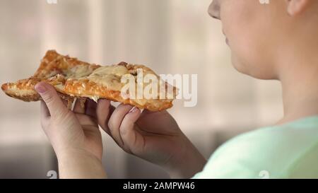 Une grosse femme qui mange des tranches de pizza, de la nourriture rapide cause l'obésité, un style de vie malsain Banque D'Images