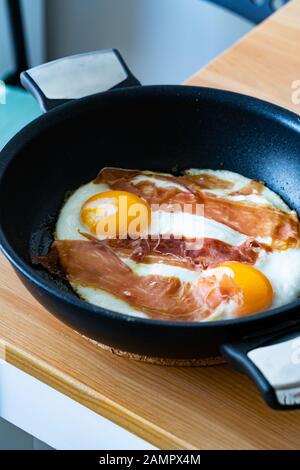 Œufs frits avec prosciutto dans la poêle pour le petit déjeuner. Prêt À Manger. Aliments Biologiques. Banque D'Images