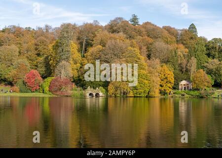 Vue sur les couleurs d'automne autour du lac à Stourhead gardens dans le Wiltshire. Banque D'Images