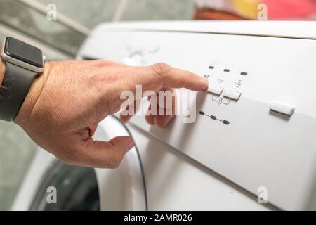 Pour les hommes, appuyez sur les boutons du lave-linge avant de faire le lavage Banque D'Images