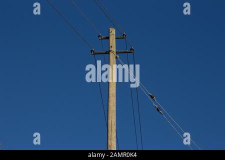 Vue à faible angle d'un pôle d'alimentation en bois et des lignes électriques et du ciel bleu Banque D'Images