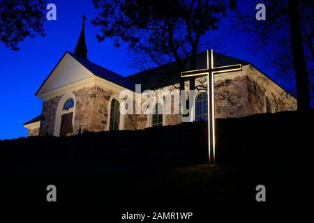 Croix éclairée devant l'église Uskela, construite en 1832 et conçue par le célèbre architecte finlandais C. L. Engel, au crépuscule d'hiver. Salo, Finlande. Banque D'Images