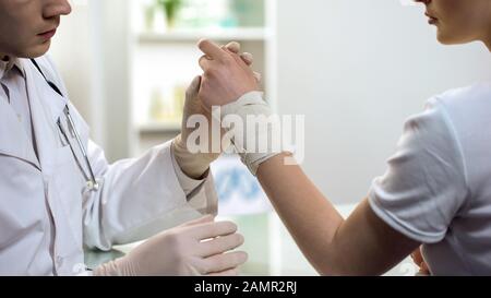 Le médecin traitant les premiers soins, bandage des femmes a étendu le poignet à l'hôpital Banque D'Images