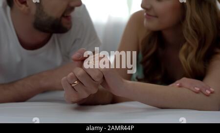 Couple tenant les mains et allongé sur le lit, se détendre en lune de miel, jeune famille Banque D'Images