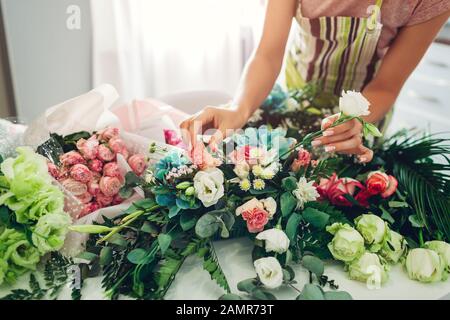 Fleuriste femme créant la composition de fleurs à la maison. Ouvrier composant le bouquet pour la Saint Valentin. Démarrage des petites entreprises Banque D'Images