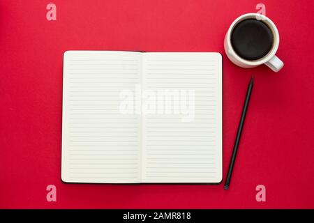 Ouvrez l'ordinateur portable avec une tasse à café sur fond rouge. Banque D'Images