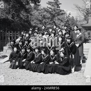 Années 1960, historique, groupe de jeunes filles en uniforme scolaire Japonais sur une sortie scolaire de poser ensemble pour une photo, le Japon. Banque D'Images