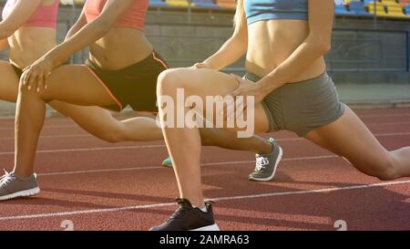 Les coureurs féminins étirent les muscles des jambes avant le marathon, l'équipe se préparant à la course Banque D'Images