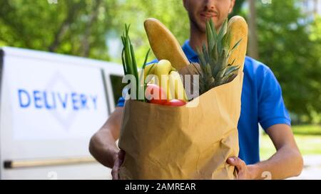 Homme de la livraison de nourriture tenant plein sac de produits frais, service de magasin en ligne Banque D'Images