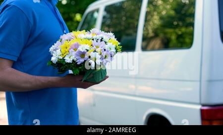 Messagerie mâle livrant des fleurs au client, expédition express à votre fête familiale Banque D'Images