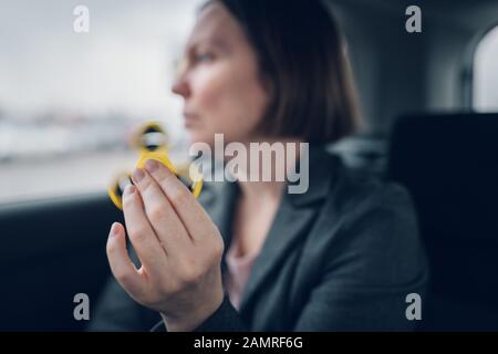 Businesswoman jouant avec fidget spinner dans la voiture pendant qu'assis à l'arrière du véhicule et se rendre à son travail, selective focus Banque D'Images