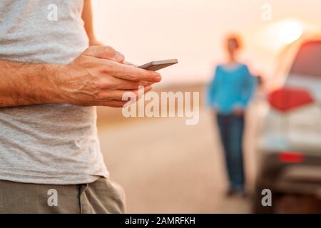 Man texting assistance routière pour véhicule est tombé en panne après le coucher du soleil en automne, selective focus Banque D'Images