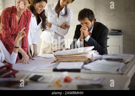 Groupe de collègues d'affaires ayant une discussion autour d'une table à l'intérieur d'une salle de réunion. Banque D'Images