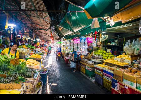 Kholng Toei marché Bangkok: Couvert markt stalsl qui vend différents fruits et légumes et une femme qui organise ses biens de décrochage Banque D'Images