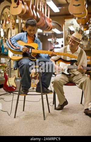 Grand-père et petit-fils en magasin à jouer de la guitare Banque D'Images