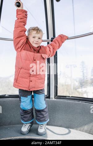 Garçon debout dans un téléphérique suspendu tenant sur une rampe, Mammoth Lakes, Californie, États-Unis Banque D'Images