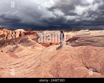 Femme randonnée dans Valley of Fire State Park avec tempête approchant, Nevada, États-Unis Banque D'Images