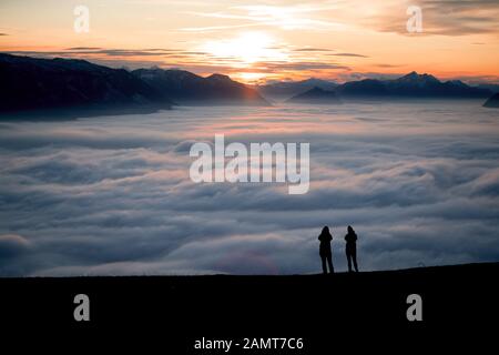 Silhouette de deux femmes sur un sommet de montagne au coucher du soleil en regardant la vue, Salzbourg, Autriche Banque D'Images