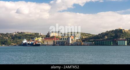 Lisbonne, Portugal - 16 mars 2016 : un navire à conteneurs passe un complexe de silos industriels dans l'estuaire du Tage à Alfama, à Lisbonne. Banque D'Images