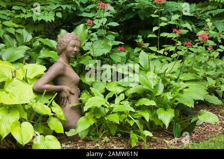 Sculpture en argile brune Nymph Goddess et plantes Hosta dans jardin zen privé de cour en été. Banque D'Images