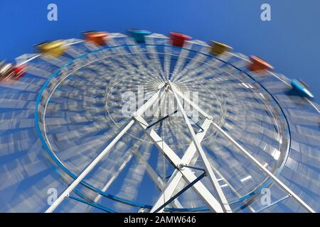 Une grande roue avec des cabines à une foire locale Banque D'Images