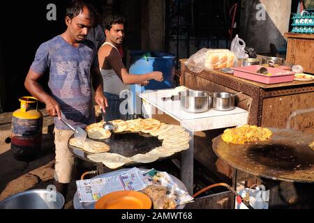Dans un restaurant pas cher situé en bordure de route dans la région de Bhendi Bazar à Mumbai (Bombay), en Inde, les cuisiniers préparent des rotis (pains plats) sur un tawa (plaque chaude) Banque D'Images