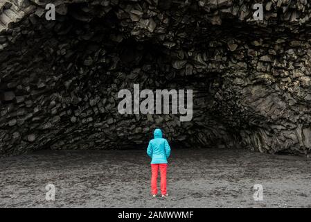 Femme de tourisme en admirant la grotte de Halsanefshellir formée en formation de basalte noire à Vik, en Islande Banque D'Images