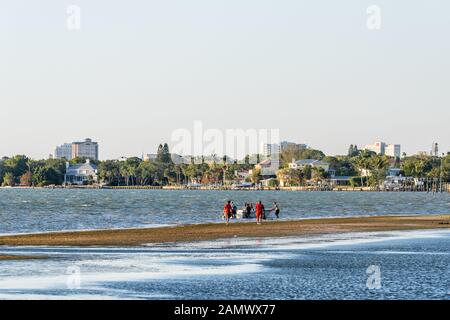 Sarasota, États-Unis - 28 avril 2018: Plage en Floride ville pendant le coucher du soleil avec paysage urbain des bâtiments de la baie et les gens marchant sur la côte de marée peu profonde à bateau Banque D'Images