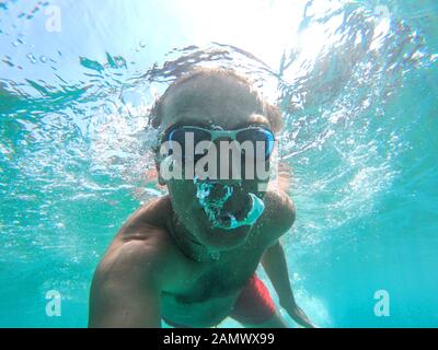 Vue sous-marine d'un plongeur jeune homme nager dans la mer. Des bulles d'air sortant de la bouche et le nez Banque D'Images