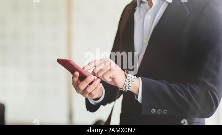 Close up of young businessman touching professionnel sur smartphone dans l'arrière-plan flou salle de réunion Banque D'Images