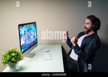 La technologie, jeux, animation, let's play et personnes concept - heureux jeune homme à lunettes avec casque jouant et gagnant le jeu de l'ordinateur à la maison Banque D'Images