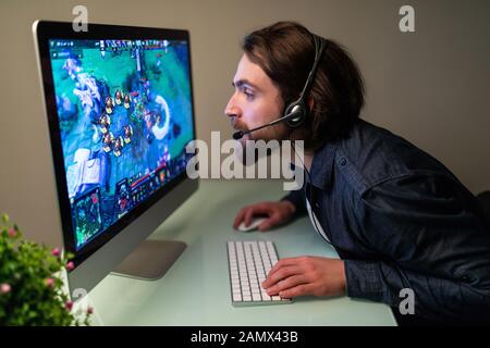 Image d'un gamer gai jouant à des jeux vidéo sur un ordinateur portant un casque Banque D'Images