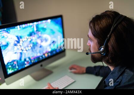 Image d'un gamer gai jouant à des jeux vidéo sur un ordinateur portant un casque Banque D'Images