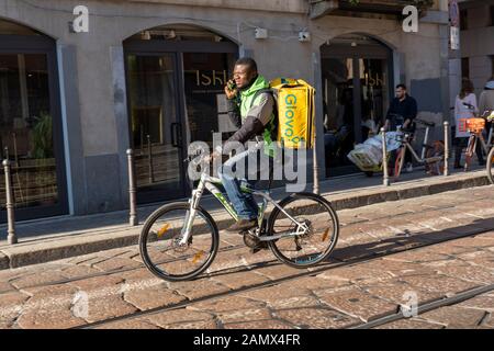 Milan, Italie - 11 janvier 2020 : Un Glovo rider cycles sur une rue du centre-ville. Service de livraison de nourriture. La commande en ligne. Banque D'Images