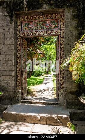 Porte en bois peinte ornée à l'entrée d'un jardin exotique. Banque D'Images