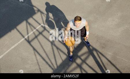 Homme caucasien jouant seul au basket-ball, dribbling ball, pratiquant des lancers libres Banque D'Images