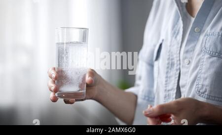 Femme prenant des analgésiques, jetant des aspirants dans le verre d'eau, les médicaments Banque D'Images