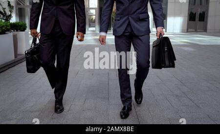 Des hommes d'affaires déterminés qui sortent du centre de bureaux et qui ont une collaboration avec des porte-documents Banque D'Images