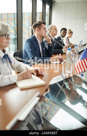 Groupe multiethnique d'hommes d'affaires assis à la table et discuter au cours de conférence de presse Banque D'Images