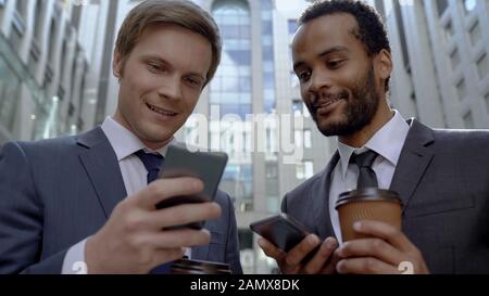 Les collègues qui se reposent sur une pause café utilisent l'application mobile pour rechercher des informations Banque D'Images