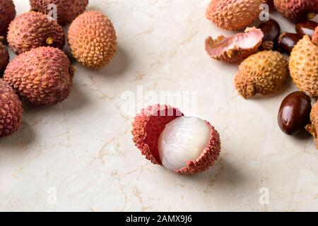 Ensemble de litchi, de coquillages et d'os près de la moitié des fruits pelés litchi (Litchi chinensis) sur une table de cuisine blanche. Les fruits et légumes, la nourriture végétarienne. Banque D'Images