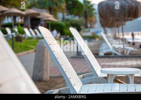 Des rangées de chaises longues et parasols de plage vide vacanciers attendent sur le bord de la mer. Selective focus, flou. Belle image du resort Banque D'Images