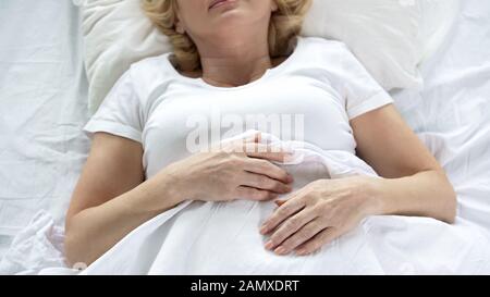 Femme âgée dormant dans son lit, vue de dessus des mains froissées, retraite, vieillesse Banque D'Images
