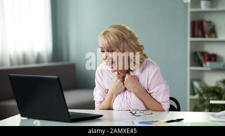 Femme de plus de 50 ans lisant un email sur la victoire de prix dans la loterie en ligne, le succès Banque D'Images
