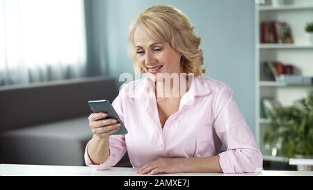 Femme adulte regardant des photos de ses enfants adultes avec chaleur et amour Banque D'Images