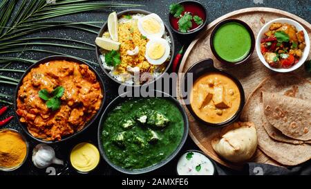 Des plats de cuisine indienne : tikka masala, paneer, samosa, chapati, chutney, épices. La nourriture indienne sur fond sombre. Assortiment repas indien haut afficher ou mettre à plat. L'espace de copie pour le texte. Banque D'Images