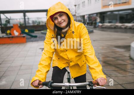 Fille en imperméable jaune équitation location sur jour de pluie Banque D'Images